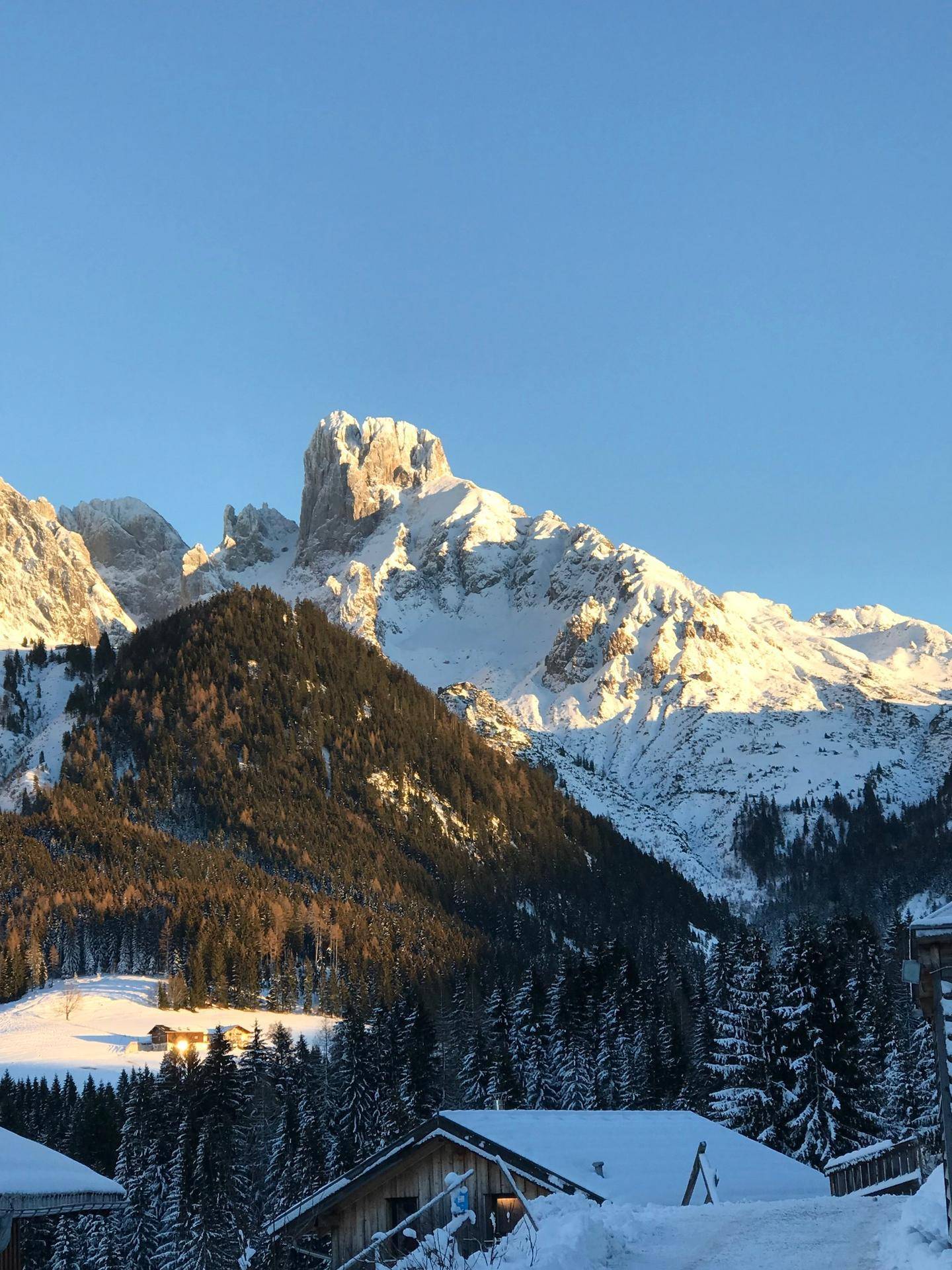 Atemberaubender Winterblick auf schneebedeckte Berge und Wälder bei Sonnenaufgang.
