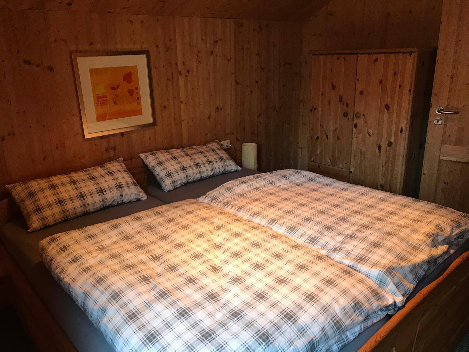 Gemütliches Schlafzimmer mit Holzvertäfelung, Doppelbett und passendem Holzschrank.