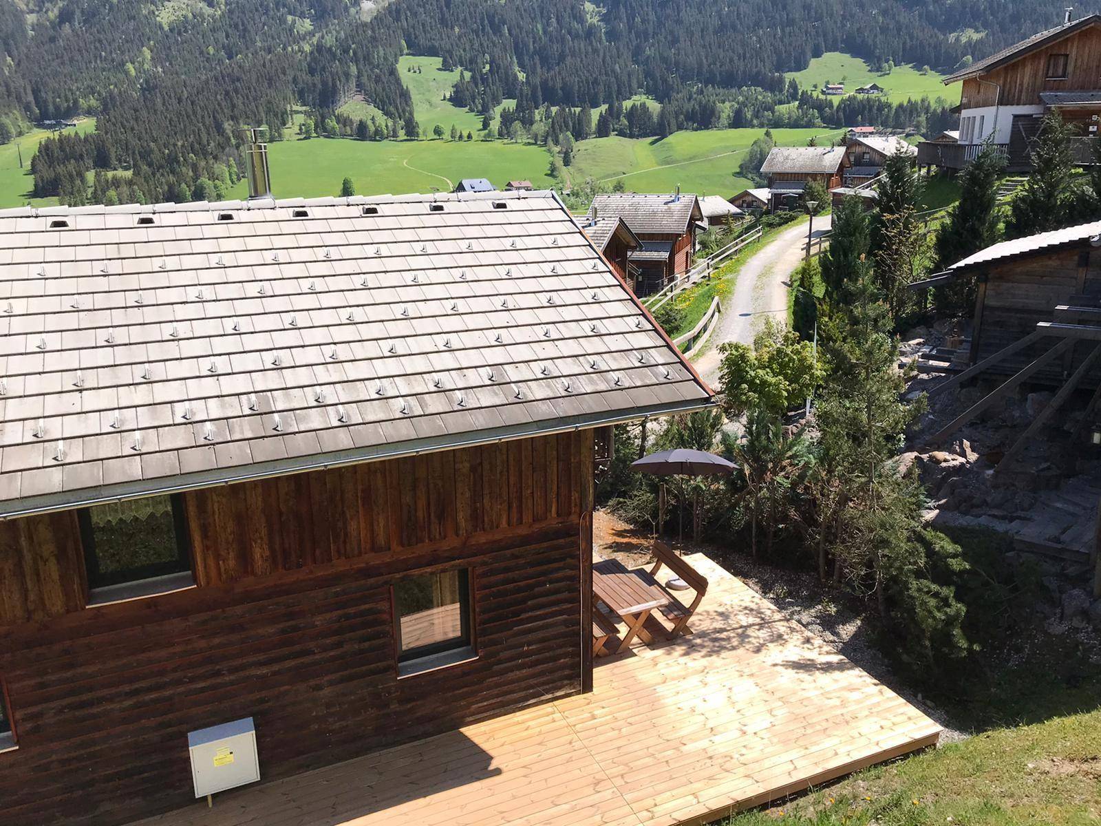 Ansicht des Holzhauses mit Terrasse und Blick auf die umliegende Berglandschaft.