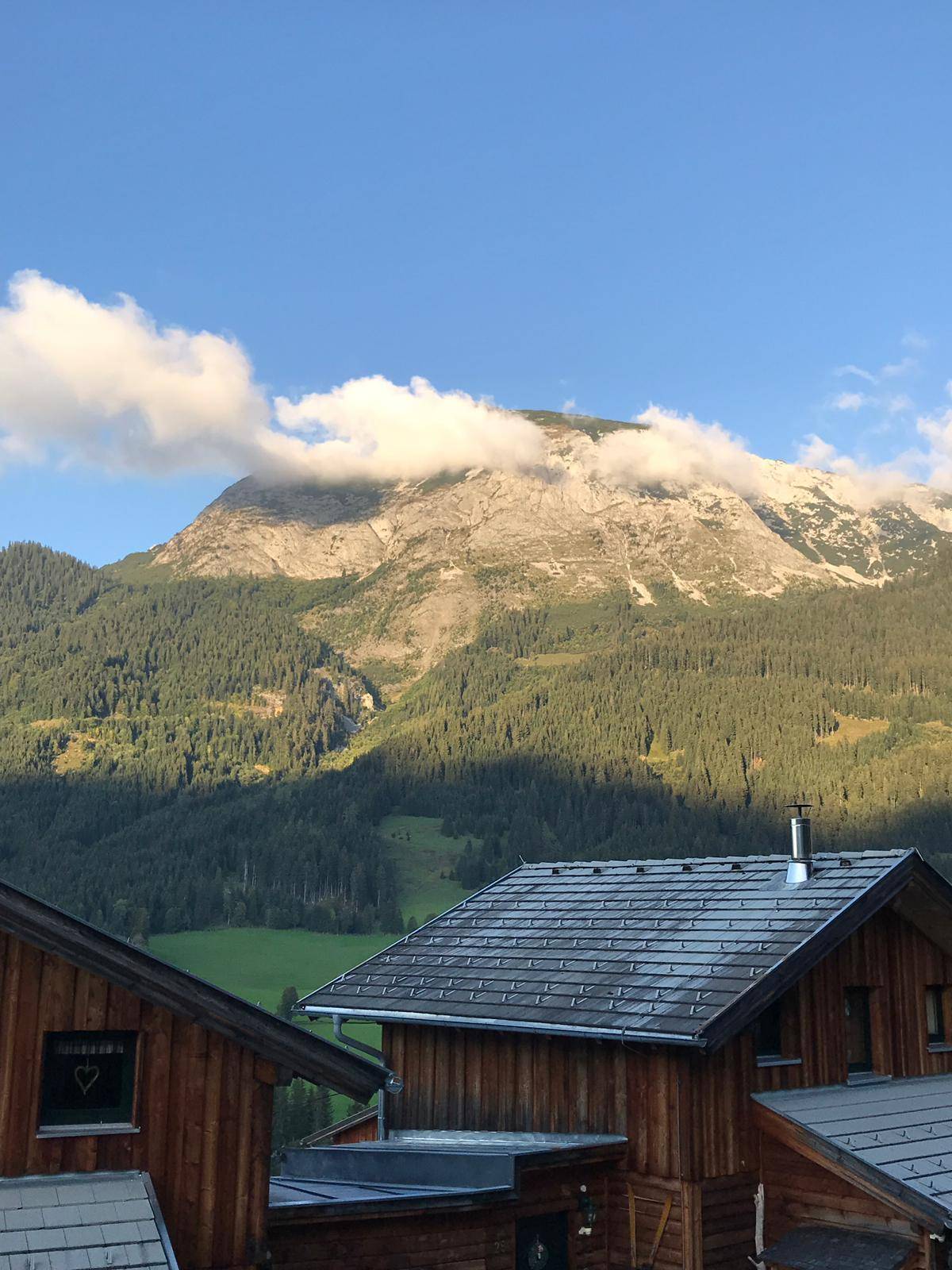 Holzhaus mit Blick auf einen majestätischen Berg, teilweise von Wolken bedeckt.