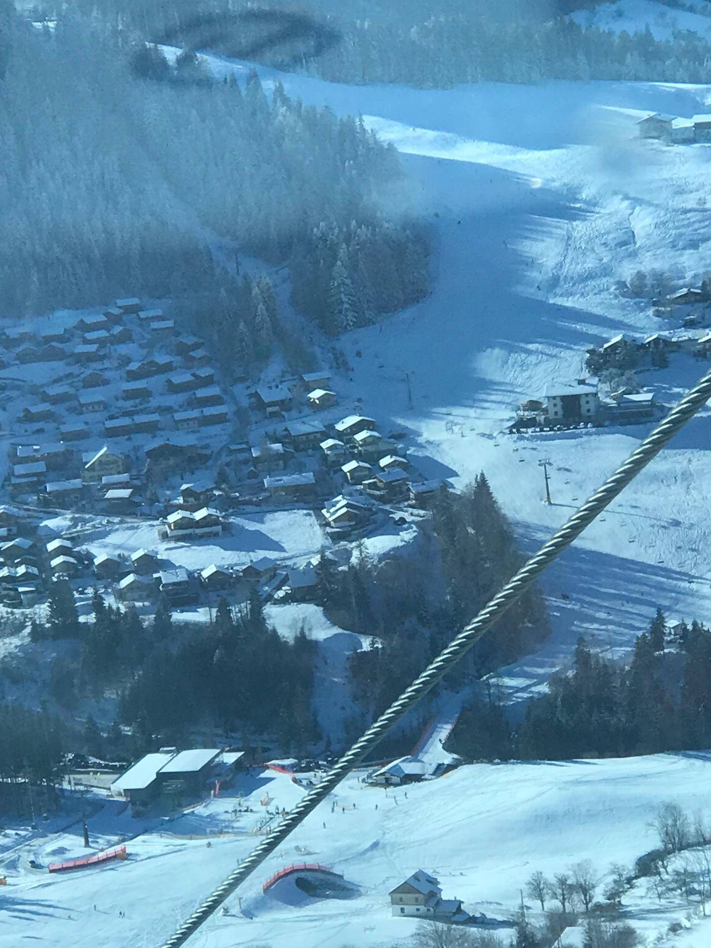 Luftaufnahme eines verschneiten Skigebiets mit vielen Häusern und Pisten.