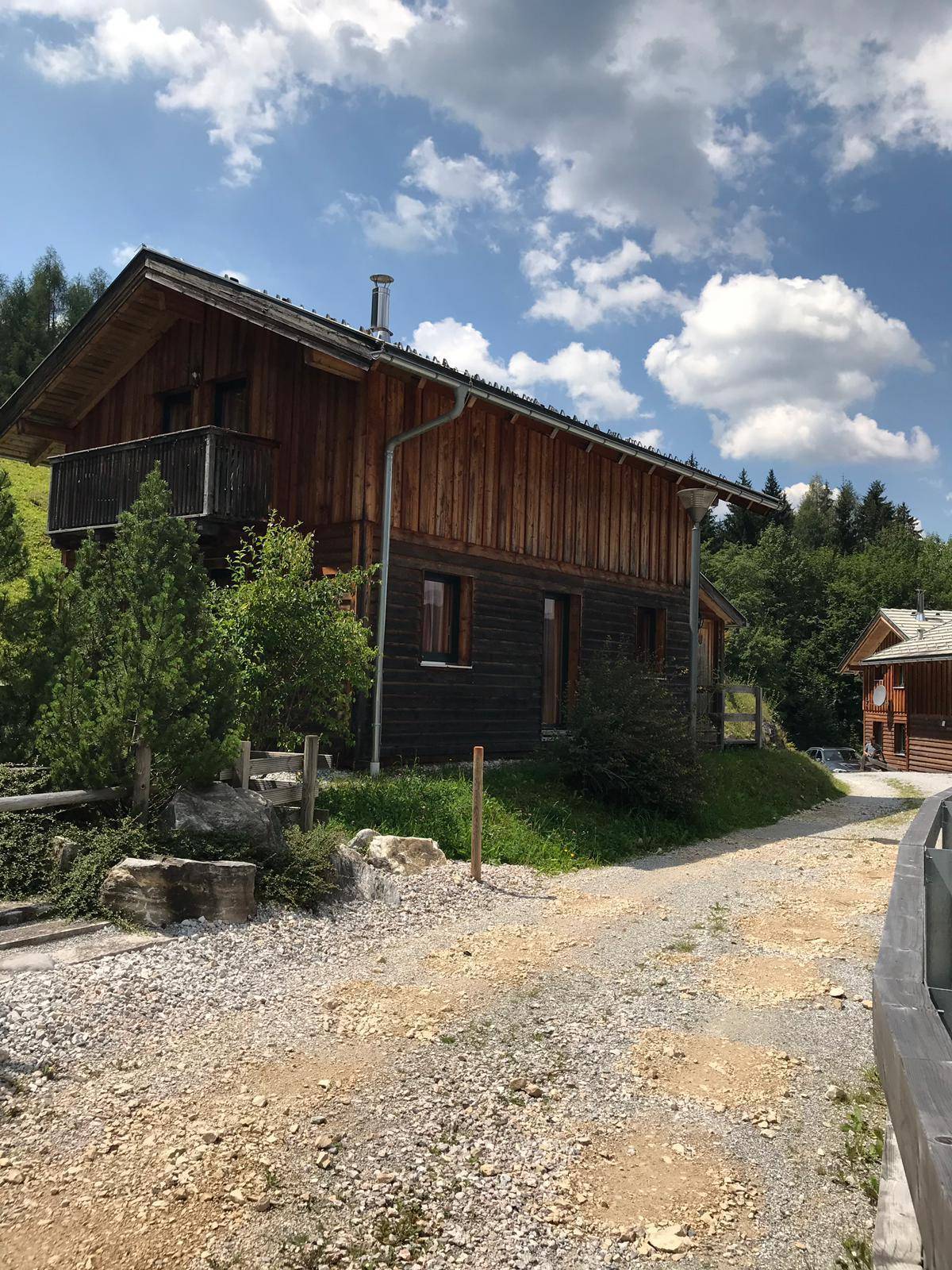 Charmantes Holzhaus in ländlicher Umgebung mit Schotterweg und Bäumen.