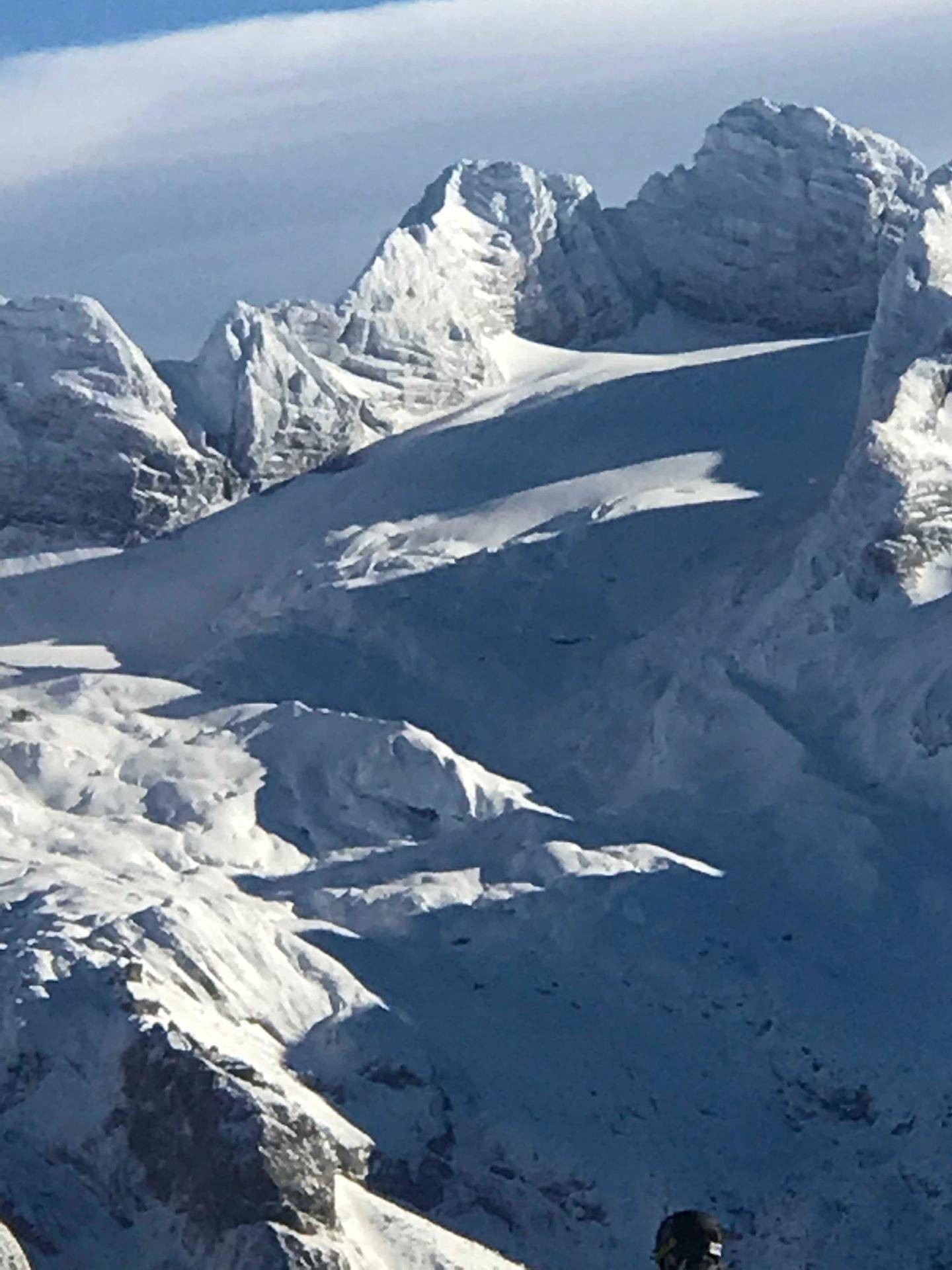 Detailansicht von schneebedeckten, zerklüfteten Berggipfeln unter blauem Himmel.