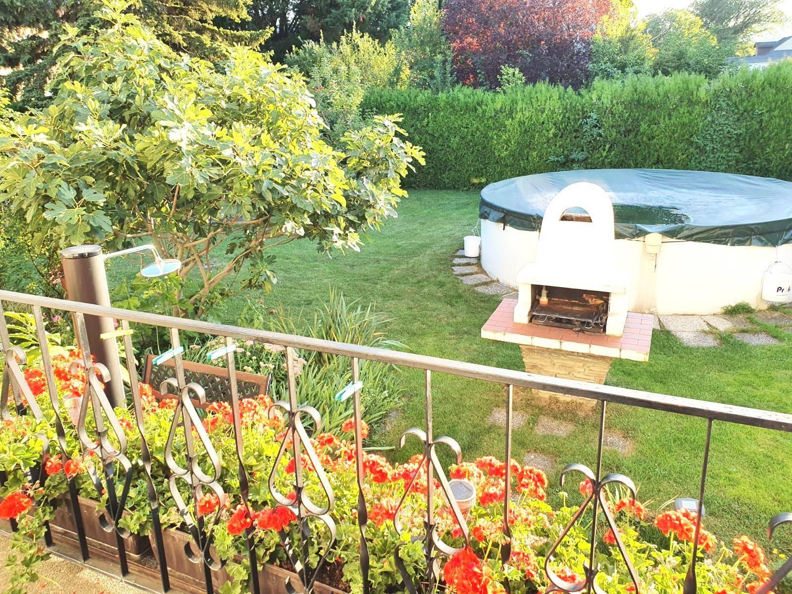 Blick vom Balkon auf den Garten mit Grillplatz, oberirdischem Pool und viel Grün.