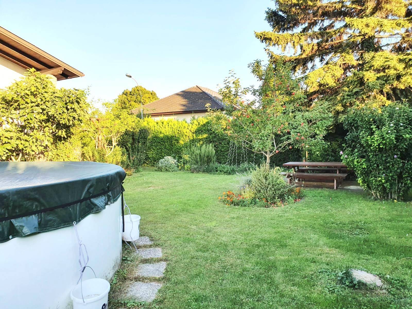 Großer Garten mit Rasenfläche, Bäumen, einem Picknicktisch und einem oberirdischen Pool.
