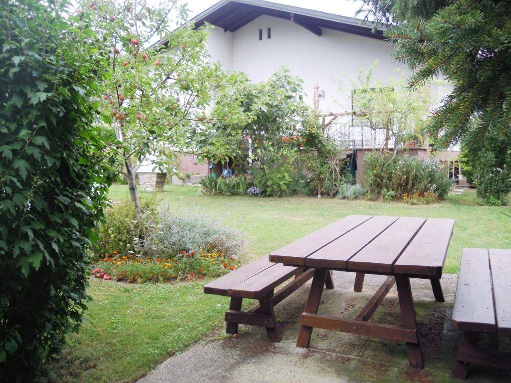 Gartenbereich mit Rasen, Obstbäumen und einem Holztisch mit Bänken für Mahlzeiten im Freien.