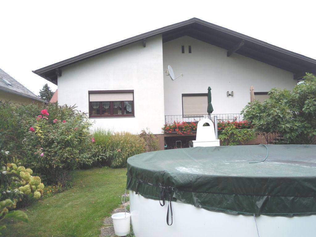 Rückansicht des Hauses mit Garten, oberirdischem Pool und einer Terrasse mit Blumenkästen.