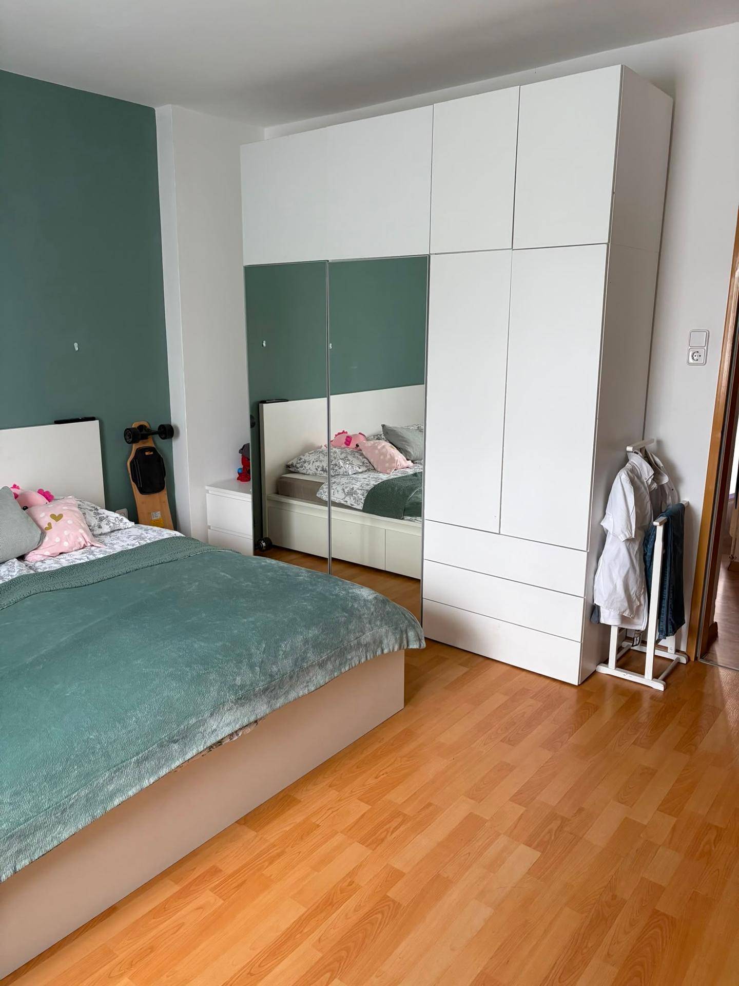 Schlafzimmer mit Holzboden, großem Kleiderschrank mit Spiegeltüren und Doppelbett.