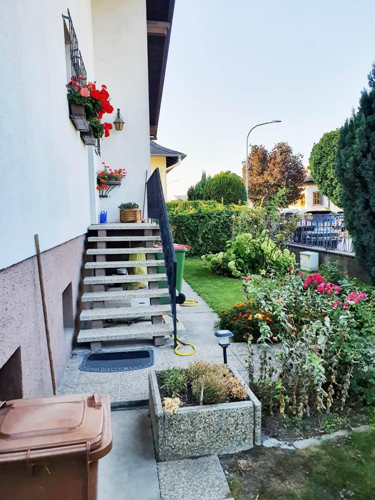 Eingangsbereich des Hauses mit Steintreppe, Blumenkästen und einem gepflegten Garten.