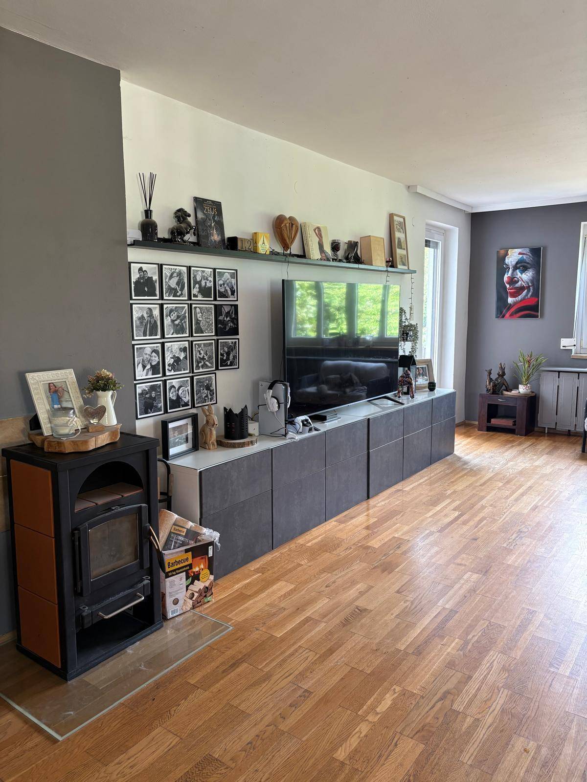 Gemütliches Wohnzimmer mit Holzboden, Kaminofen und moderner TV-Wandgestaltung.
