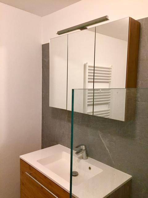 Modernes Badezimmer mit Einzelwaschbecken, Holzunterschrank und Spiegelschrank.