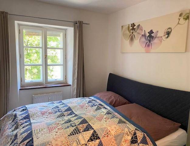 Schlafzimmer mit Doppelbett, Holzboden und Kunstwerk über dem Bett.