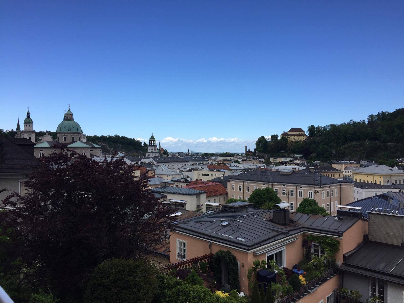 Panoramablick über die historische Stadt mit Dächern und Bergen im Hintergrund.