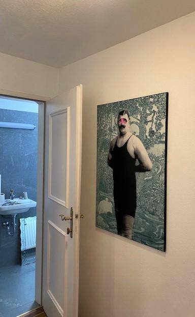 Flur mit weißer Tür, die zu einem Badezimmer mit Waschbecken führt.