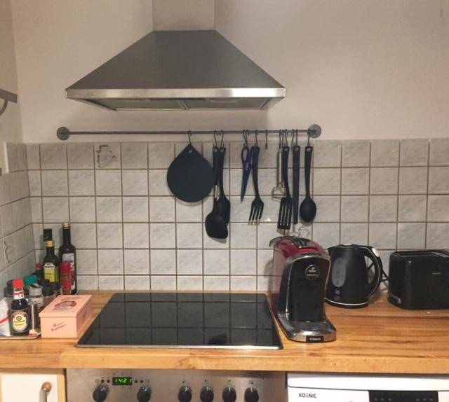 Küchenzeile mit Induktionskochfeld, Dunstabzugshaube und Kaffeemaschine auf Holzarbeitsplatte.