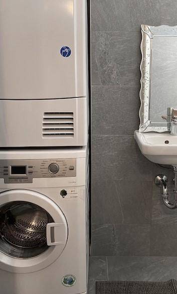 Waschküche mit Waschmaschine, Trockner und kleinem Waschbecken.