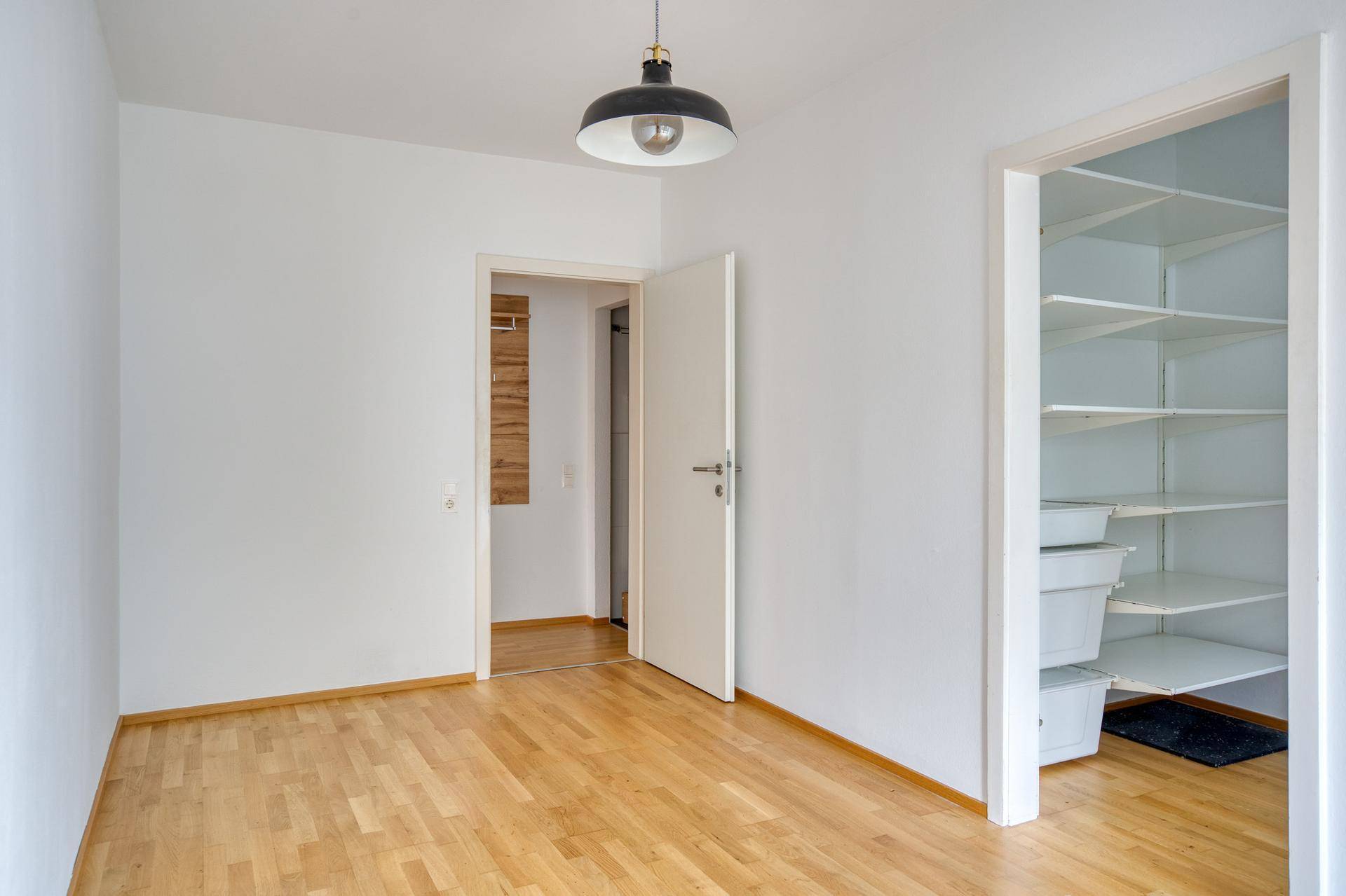 Schlafzimmer mit Parkettboden, weiß gestrichenen Wänden und praktischem Einbauschrank.