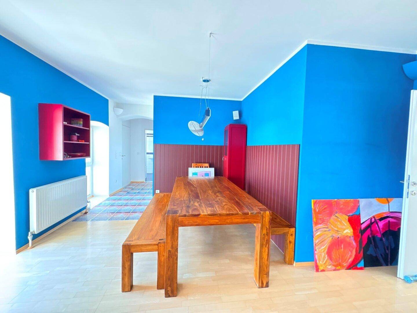 Essbereich mit leuchtend blauen Wänden, rustikalem Holztisch und passender Sitzbank.