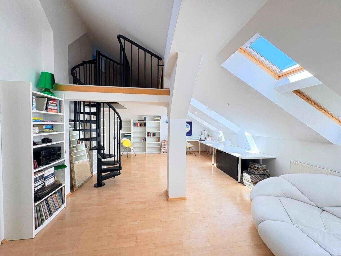 Geräumiges Dachgeschoss mit Wendeltreppe, Bücherregalen, Arbeitsbereich und hellen Dachfenstern.