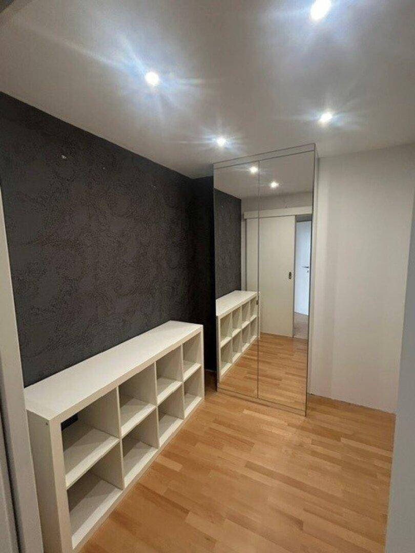 Kleiner Raum mit Spiegelschrank, Regalen und Holzparkettboden, ideal als Ankleide.