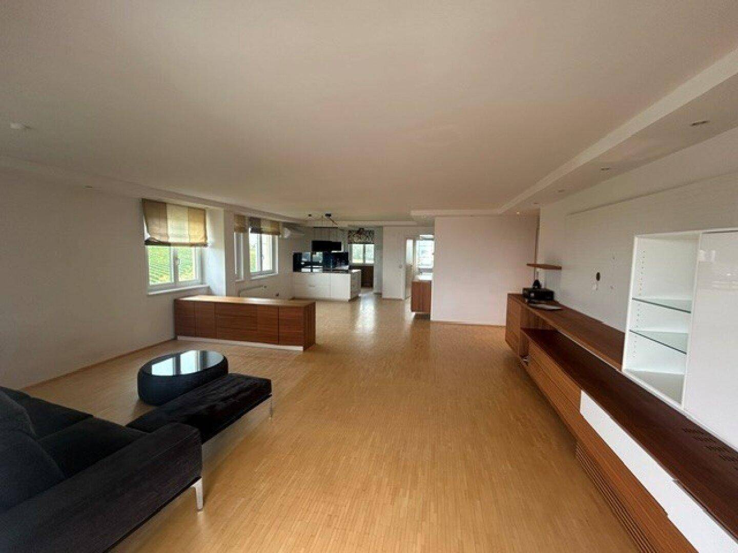 Geräumiges Wohnzimmer mit Parkettboden, modernen Möbeln und viel Tageslicht.
