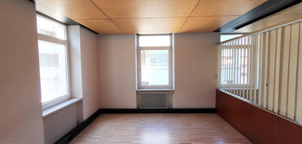 Innenraum mit Holzdeckenverkleidung, Parkettboden und einem Geländer, das auf eine untere Ebene blickt.