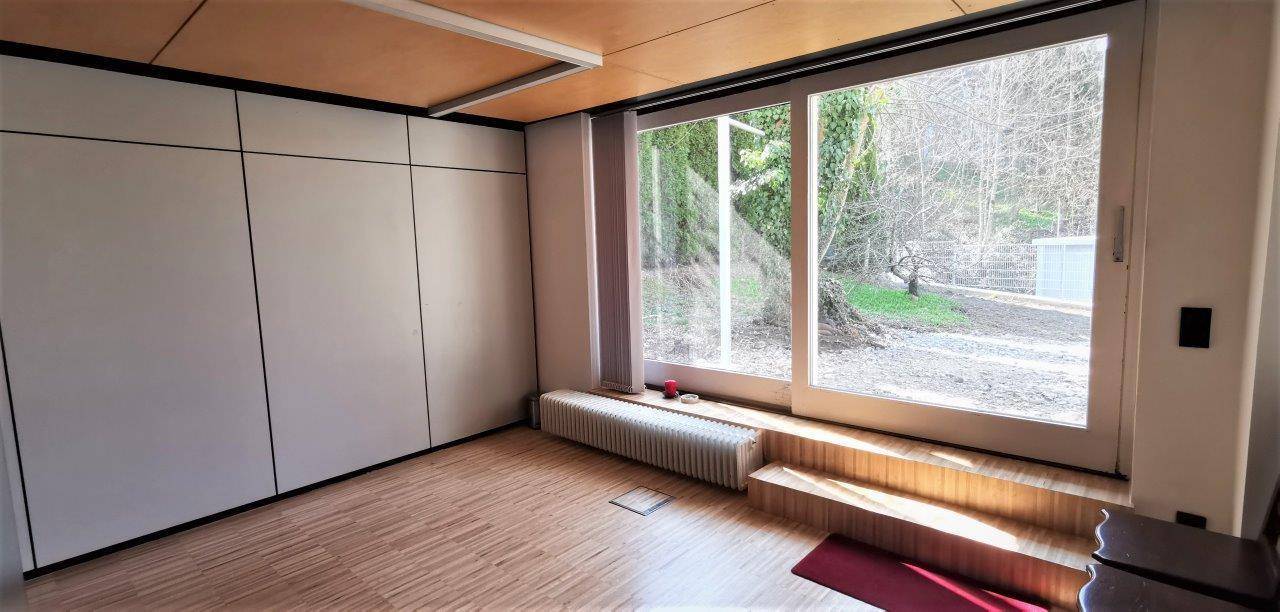 Heller Raum mit großer Fensterfront zum Garten und integrierten Wandschränken.