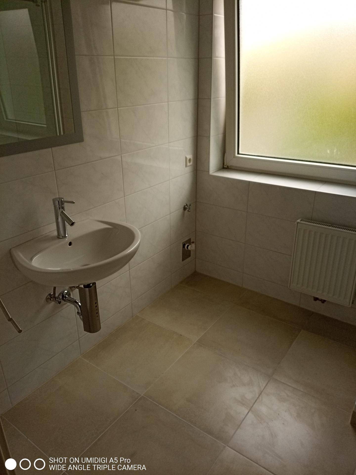 Modernes Badezimmer mit Waschbecken, Spiegelschrank und Fenster.