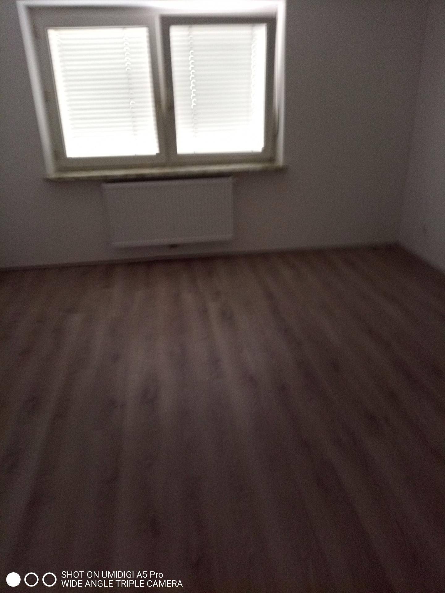 Leeres Zimmer mit Laminatboden, Fenster und Heizkörper, ideal als Schlafzimmer.