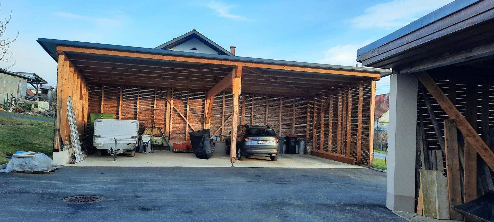 Geräumiger Holzcarport bietet geschützten Stellplatz für Fahrzeuge und zusätzlichen Stauraum.