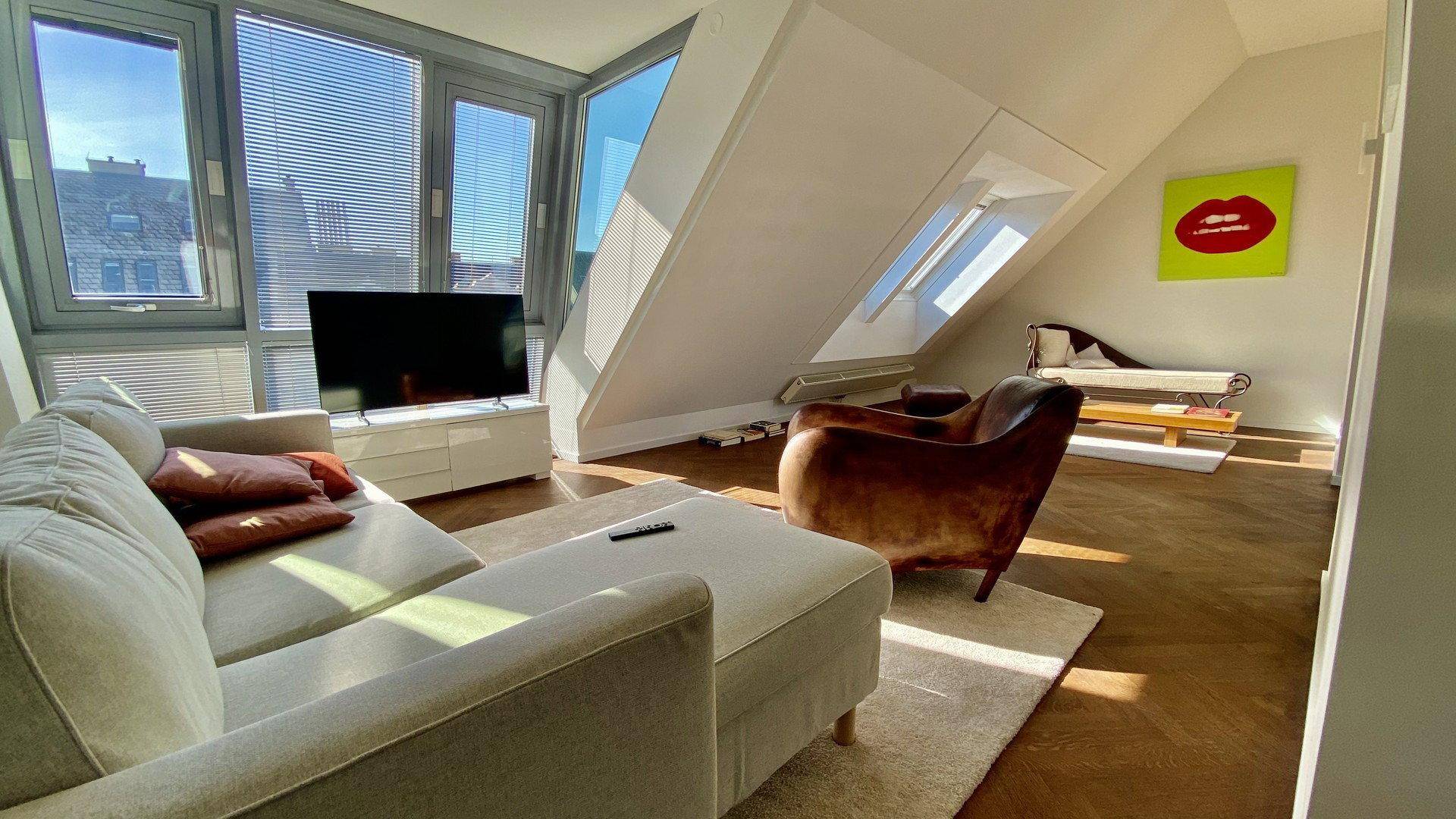 Lichtdurchflutetes Wohnzimmer mit großen Fenstern, Holzboden und gemütlicher Sitzecke.