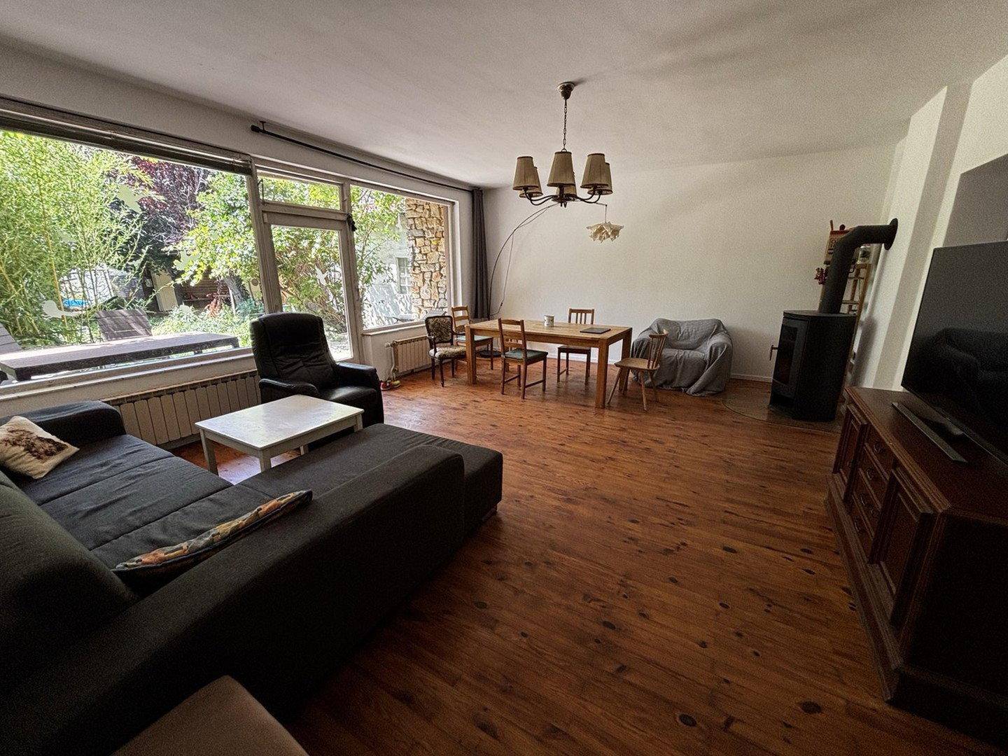 Heller Wohnbereich mit Holzboden, großzügigen Fenstern und Blick in den Garten.