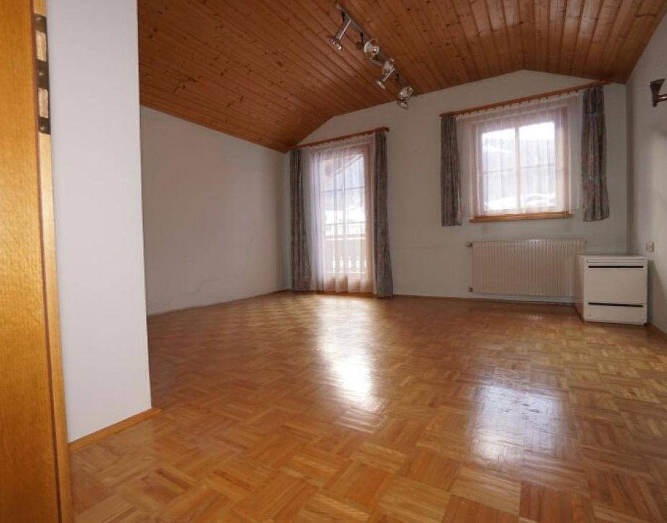 Gemütliches Schlafzimmer mit Holzdielenboden, Dachschräge und Zugang zu einem französischen Balkon.