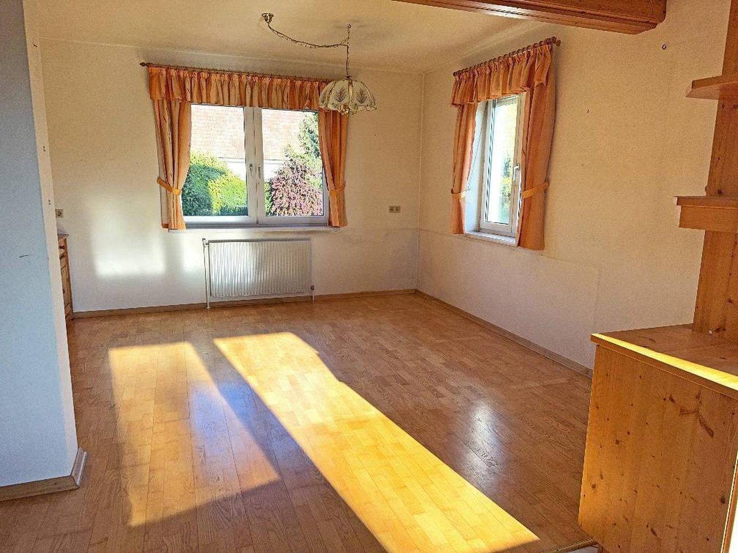 Heller Essbereich mit Holzfußboden und zwei Fenstern, bereit zur individuellen Einrichtung.