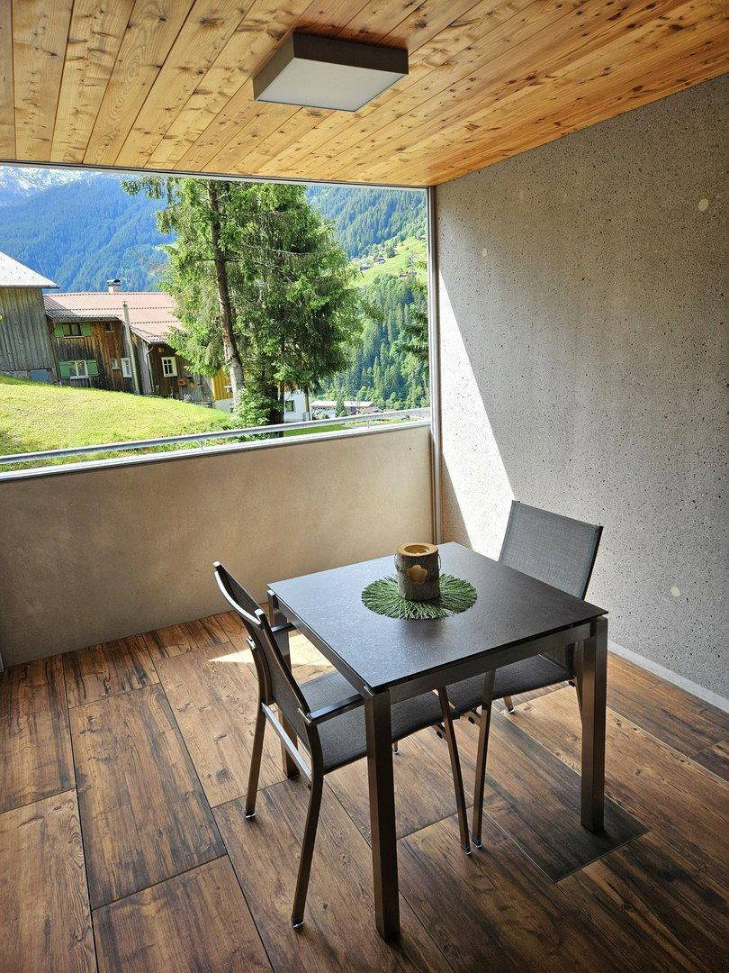 Gemütlicher Balkon mit Holzboden, Sitzgelegenheiten und weitem Blick auf die umliegende Natur.