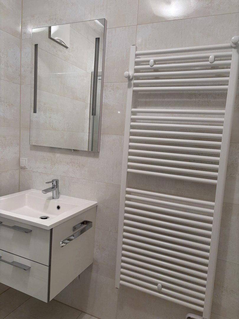 Kleines Badezimmer mit Waschbecken, Spiegel und beheiztem Handtuchhalter.