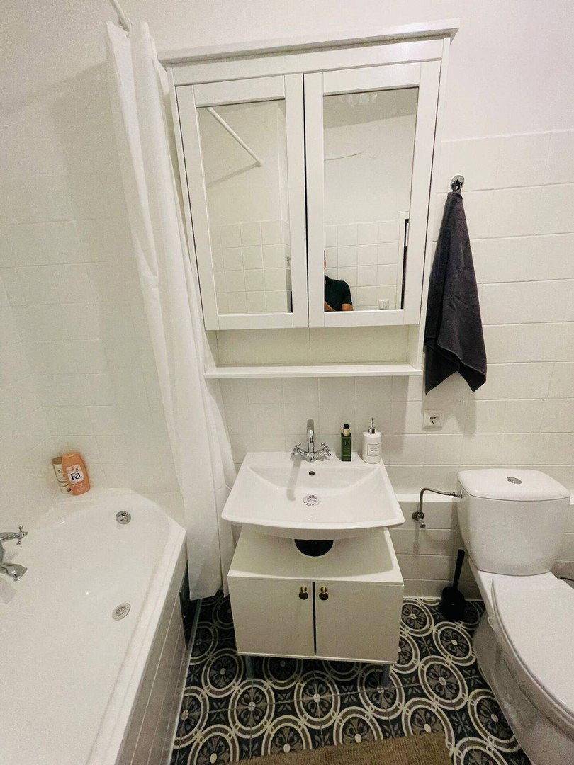 Badezimmer mit Waschbecken, Toilette, Spiegelschrank und Badewanne mit Duschvorhang.