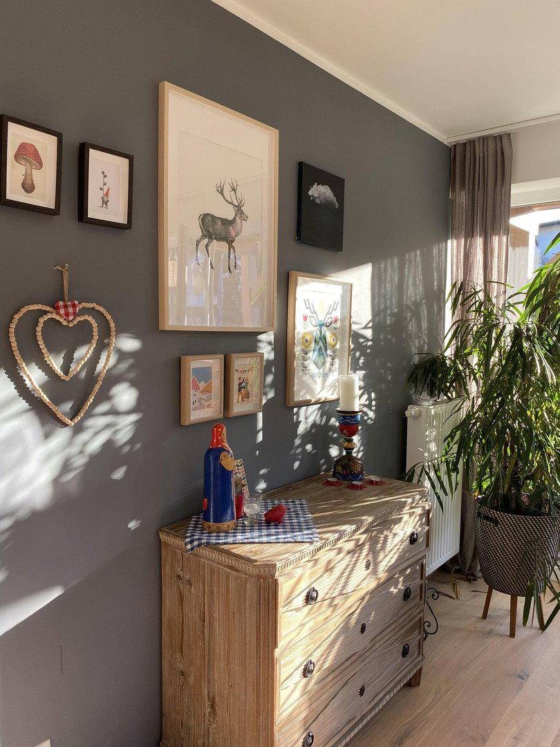 Flur mit Holzkommode, Pflanzen und Wanddekoration in warmem Licht.