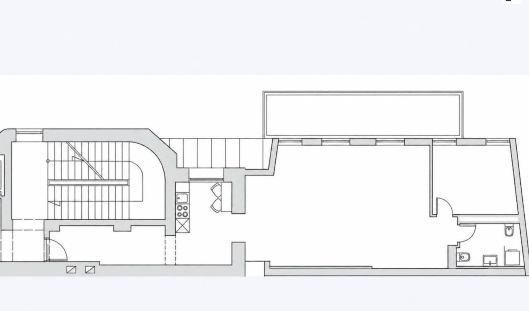 Grundrissplan zeigt eine offene Raumaufteilung mit Treppe, Küchenbereich, großem Raum und Badezimmer.