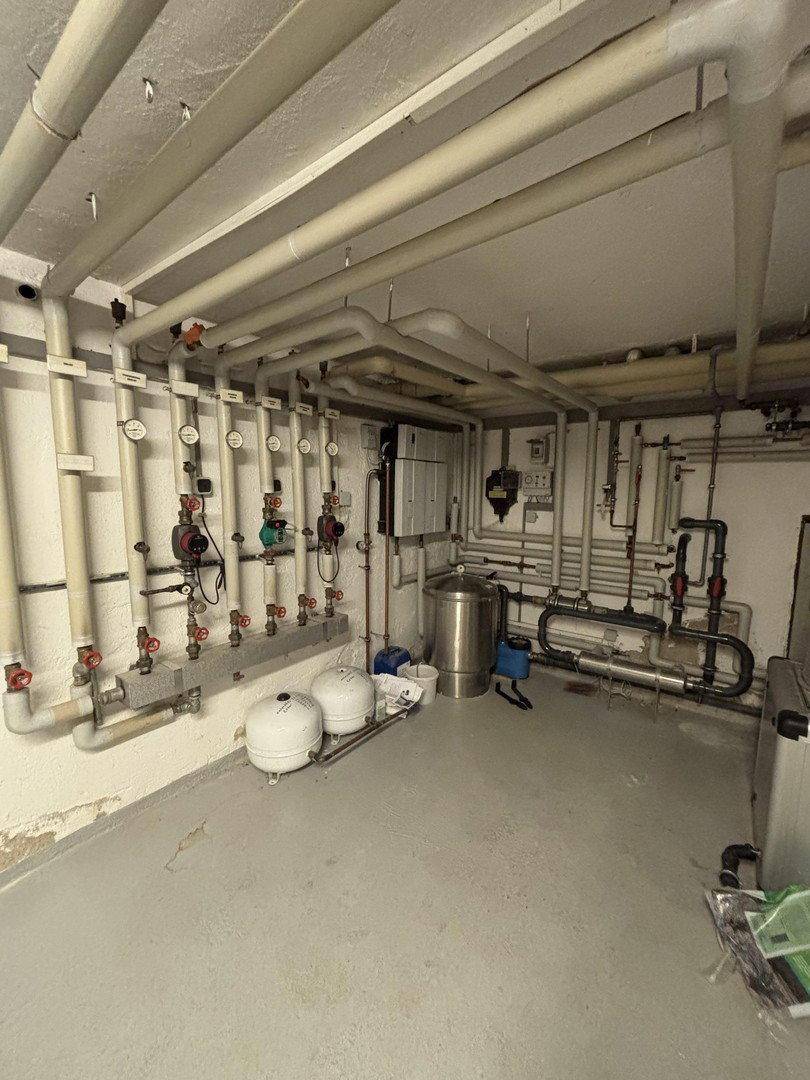Heizungsraum mit umfangreicher Rohrinstallation und technischen Anlagen im Keller.