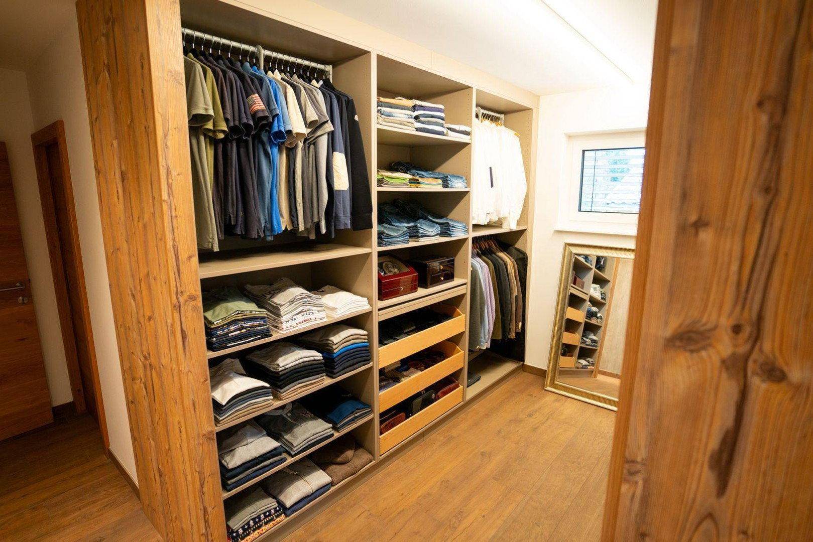 Geräumiger begehbarer Kleiderschrank mit offenen Regalen und viel Stauraum für Kleidung.