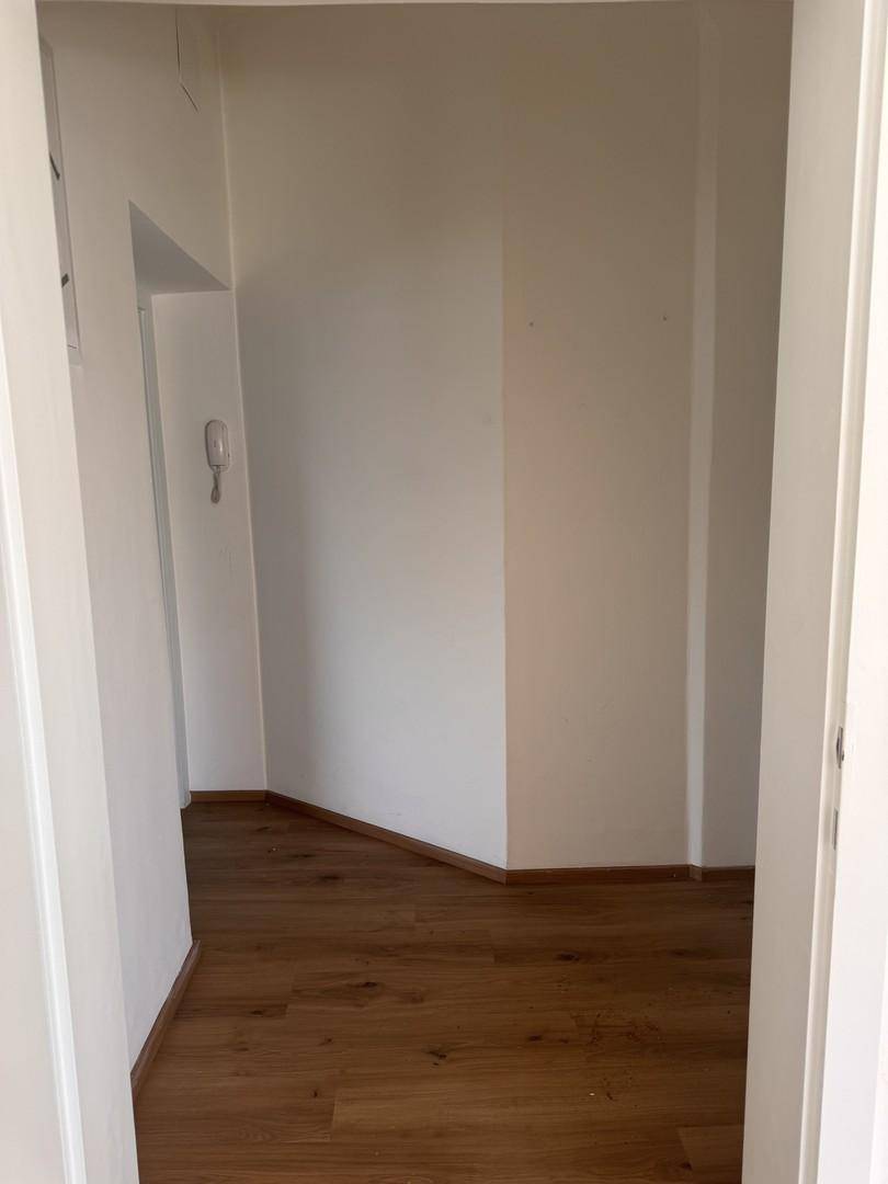 Schlichter Flurbereich mit Holzboden und weißen Wänden, der zu weiteren Räumen führt.