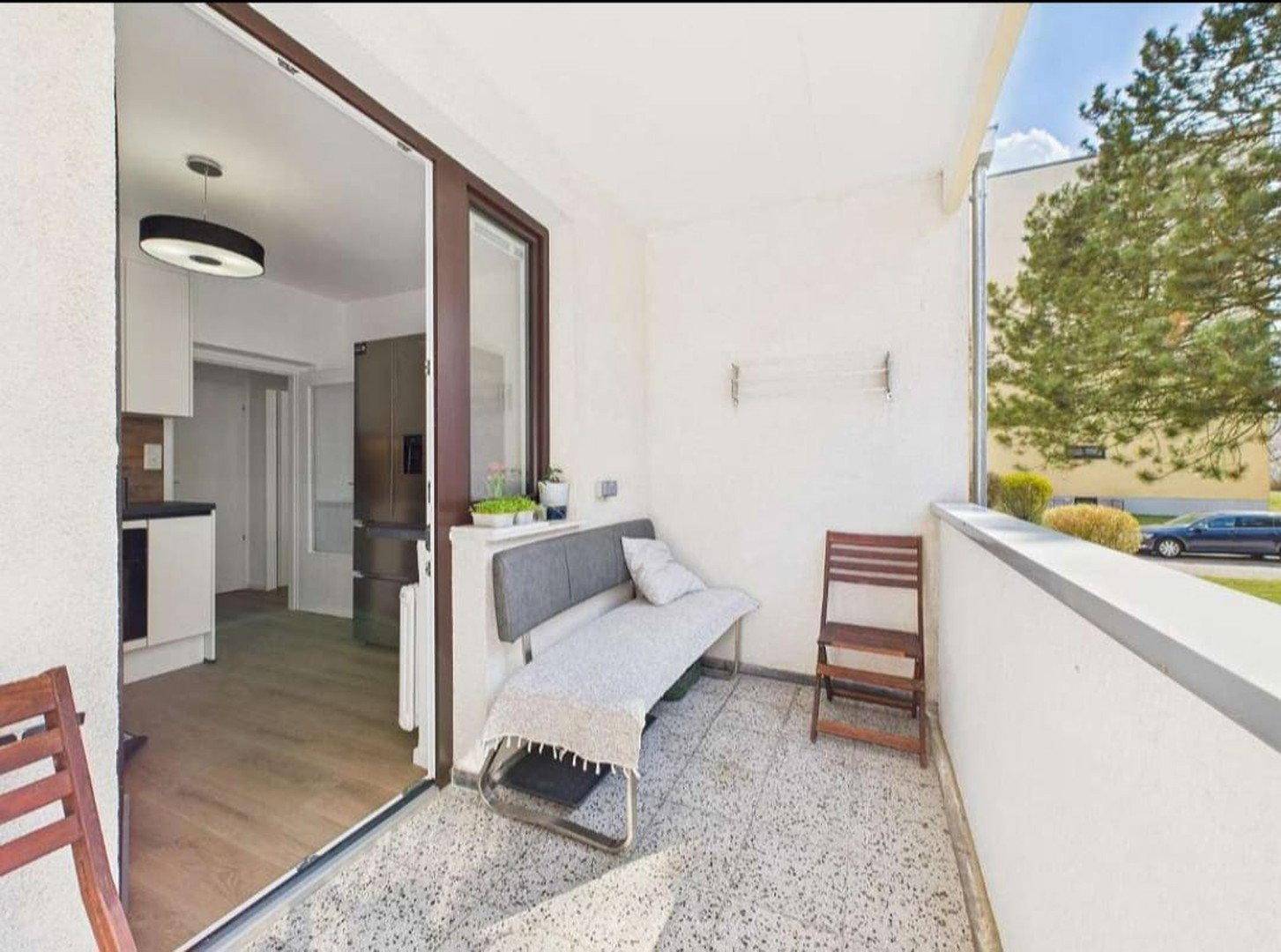 Sonniger Balkon mit Sitzgelegenheiten und direktem Zugang zur Küche.