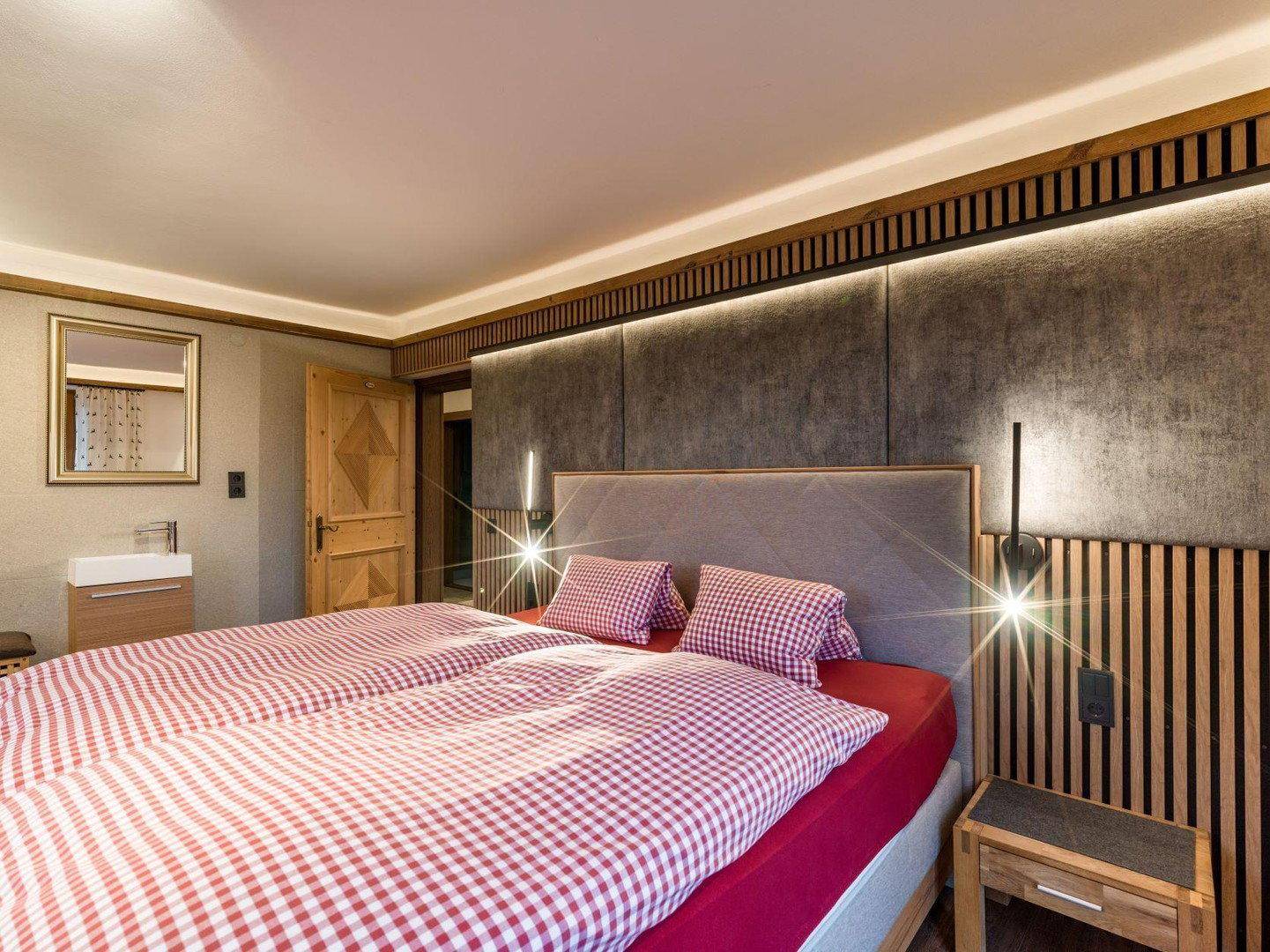 Schlafzimmer mit gemütlichem Doppelbett, Holzelementen und indirekter Beleuchtung.
