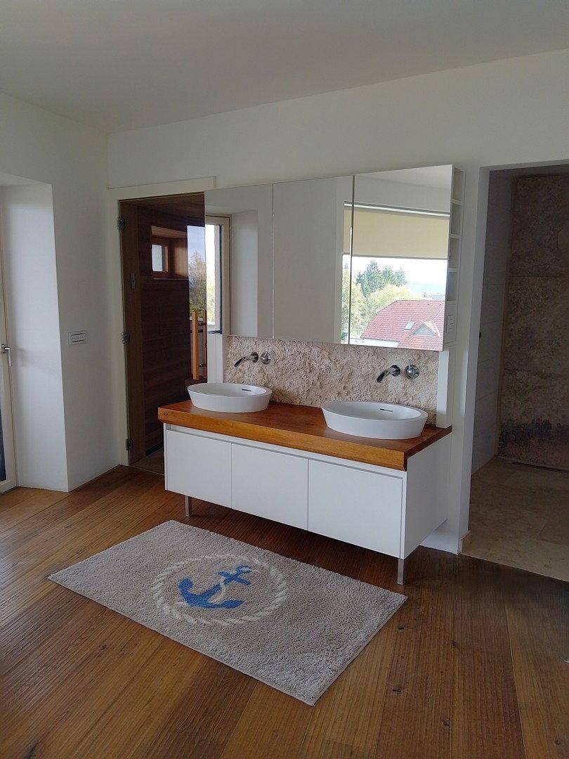 Modernes Badezimmer mit Doppelwaschbecken, Holzplatte und angrenzender Sauna.
