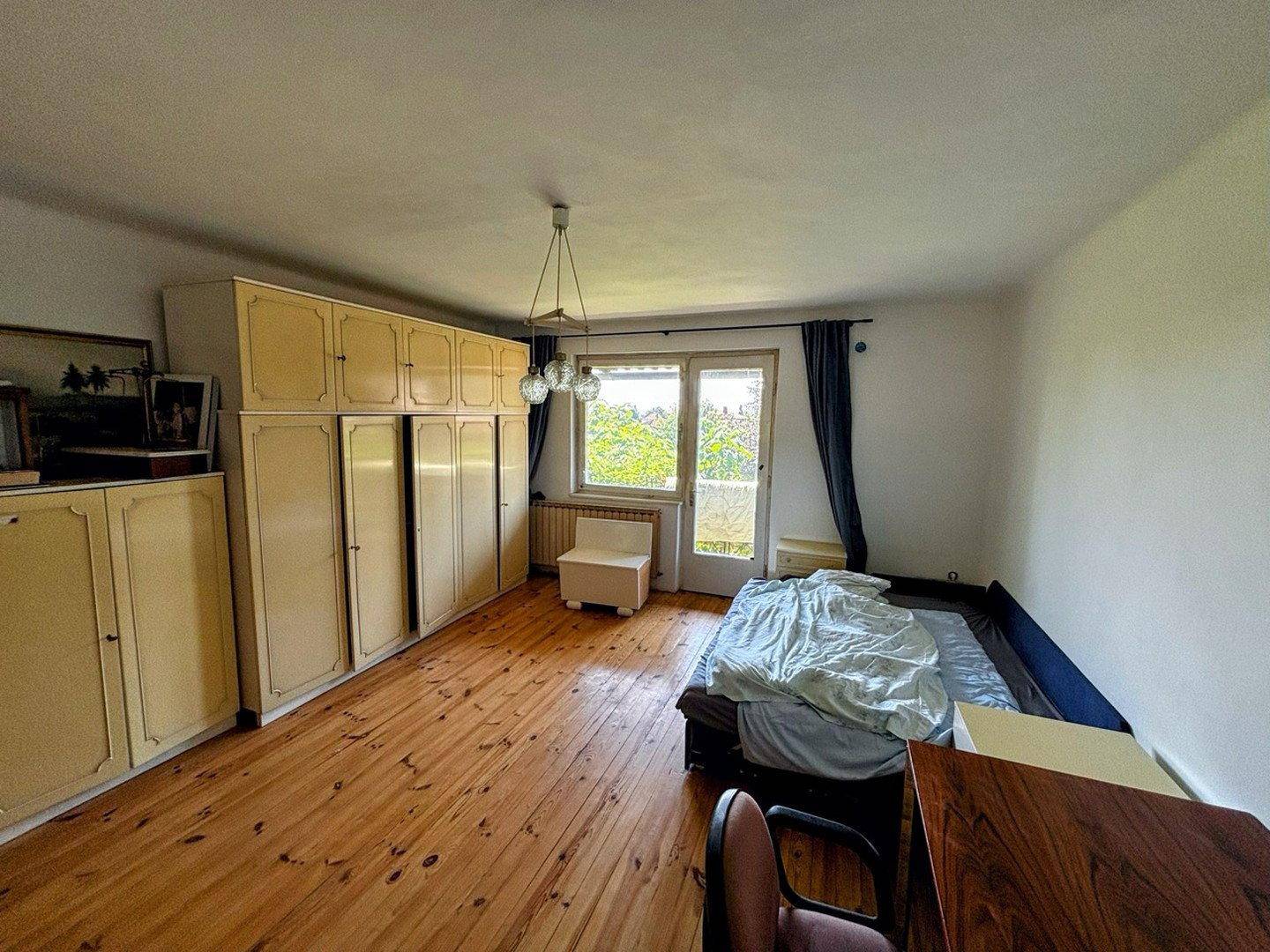 Helles Schlafzimmer mit Holzboden, großen Fenstern und geräumigen Kleiderschränken.
