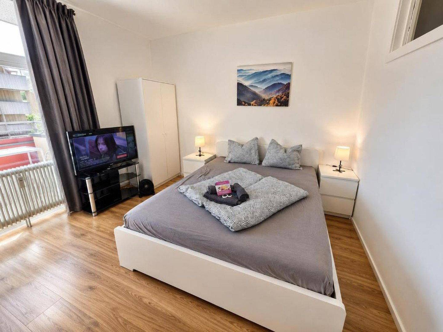 Gemütliches Schlafzimmer mit Doppelbett, Nachttischen und direktem Zugang zum Balkon.
