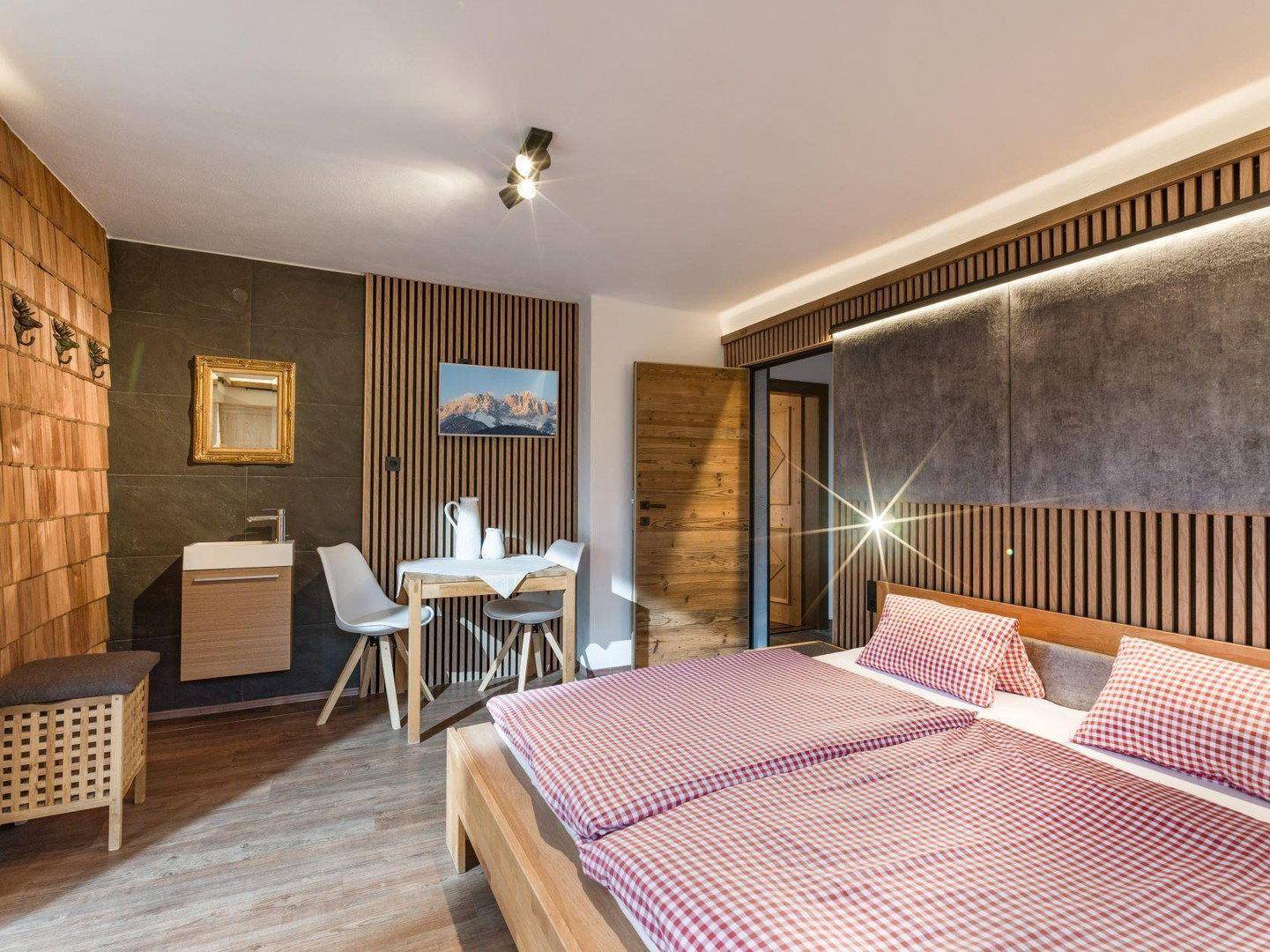 Schlafzimmer mit Doppelbett, Holzwänden und integriertem Waschbecken.
