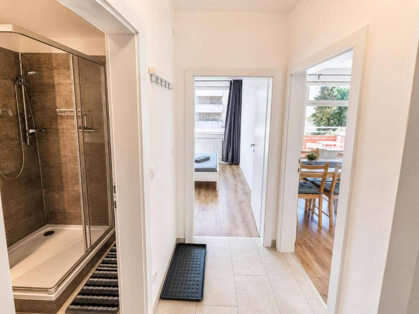 Heller Flur mit Blick in das Badezimmer und einen weiteren Wohnbereich.