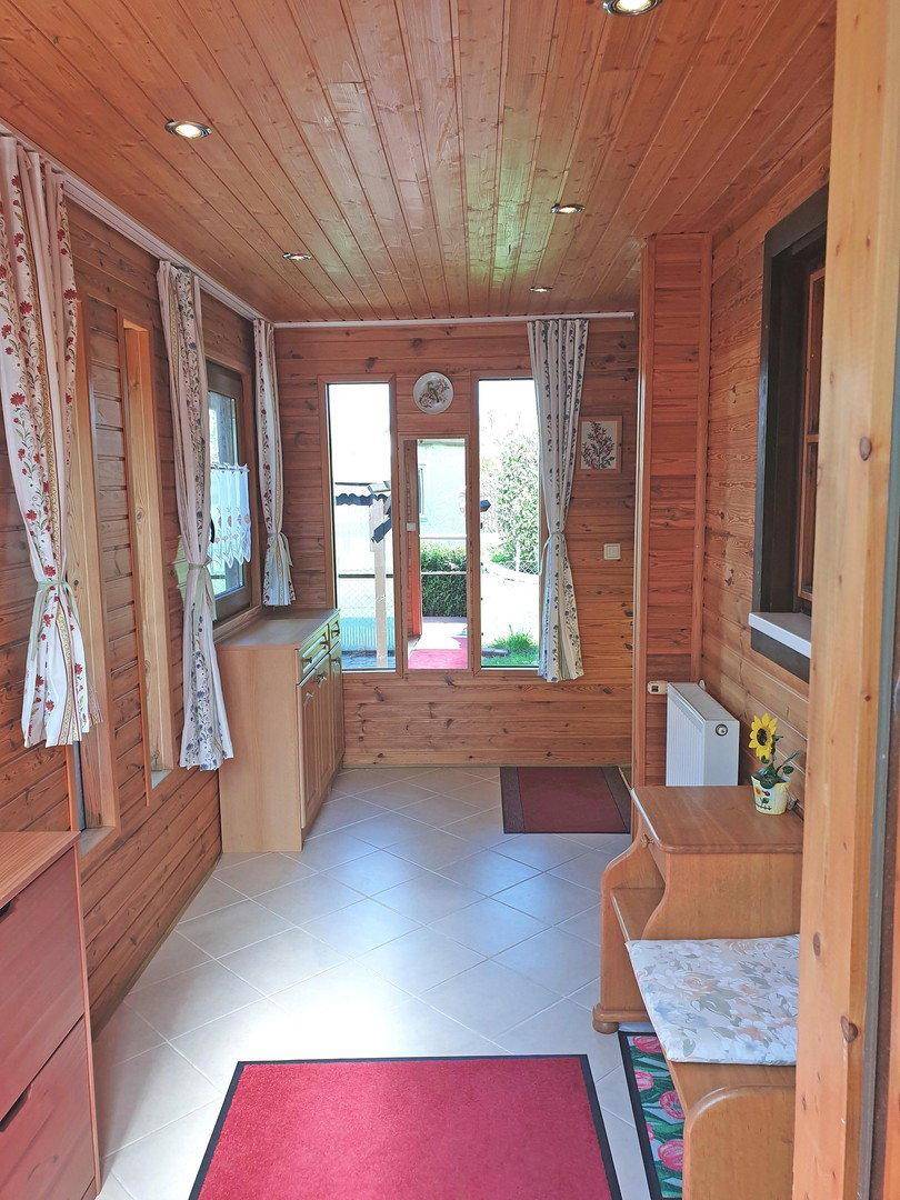 Heller Eingangsbereich mit Holzvertäfelung, Fliesenboden und natürlichem Lichteinfall.